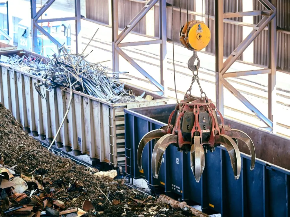 Recycling yard mein crane se scrap metal uthaya ja raha hai
